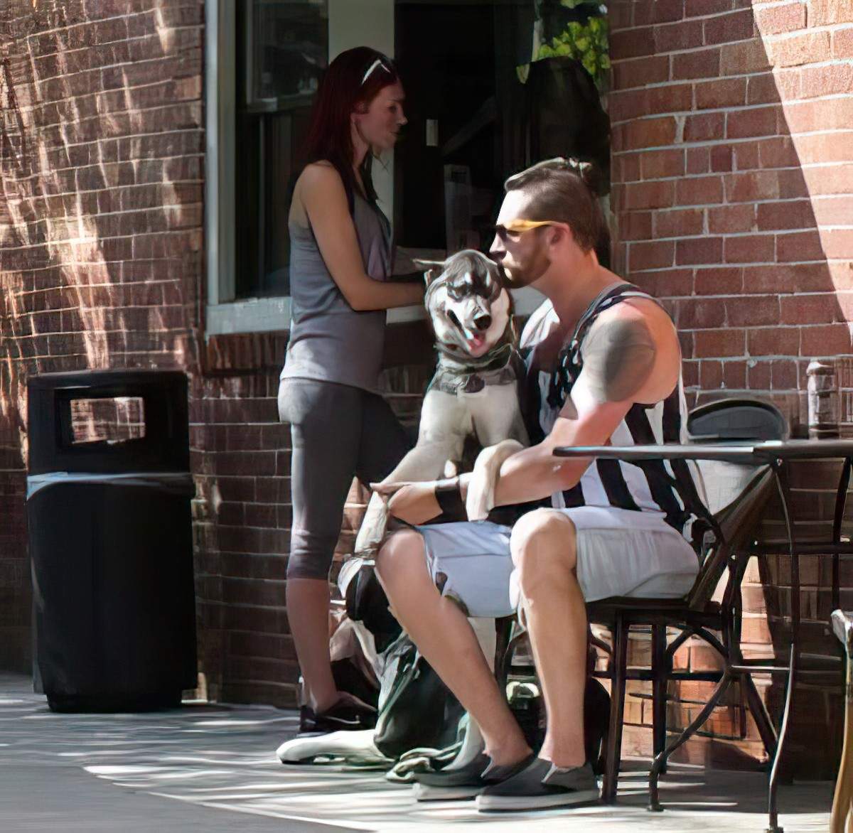 A person and a dog sitting on a chair outside a building